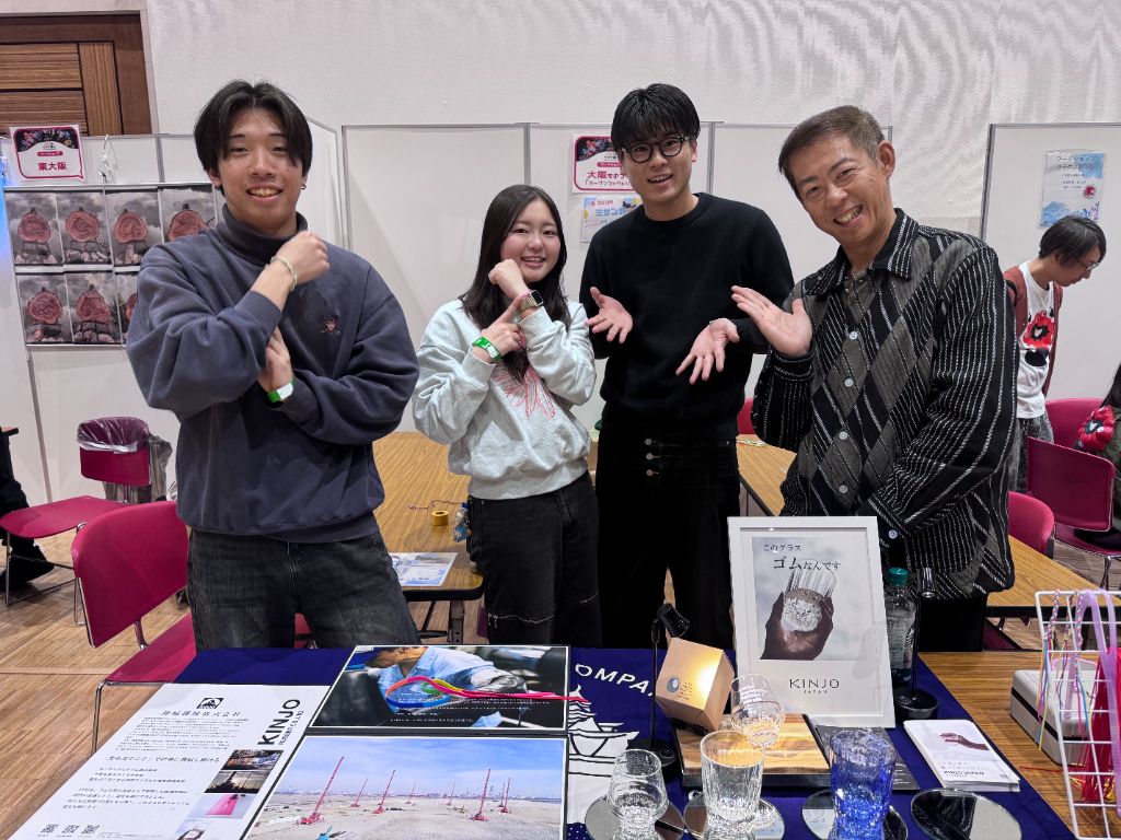 野外イベントのブースで子どもたちの工作をスタッフが丁寧にサポートする様子