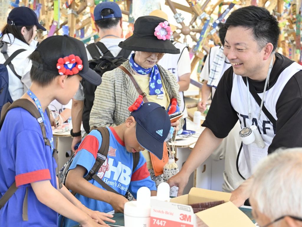 イベント会場でスタッフが来場者の子どもたちと笑顔で交流する様子